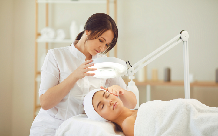 Woman performing a facial course consultation on a client’s face